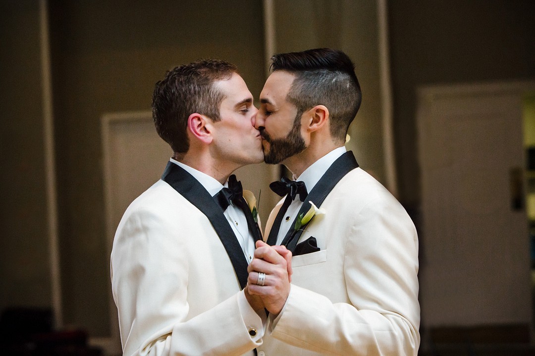 two grooms in love kiss at their wedding