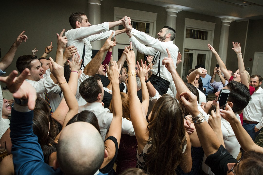 two grooms celebrate their wedding with jewish chair dance