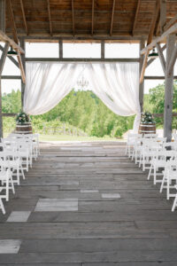 barn wedding with white chairs and wine barrels