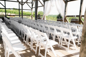 white garden chairs in rows for ceremony in barn at winery