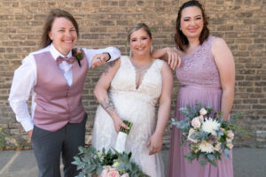 bride standing with two bridesmaids holding flowers