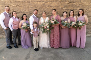 bride standing with wedding party holding flowers. ring bearer.