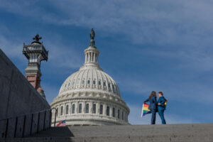 two brides holing rainbow flag at library of congress kissing